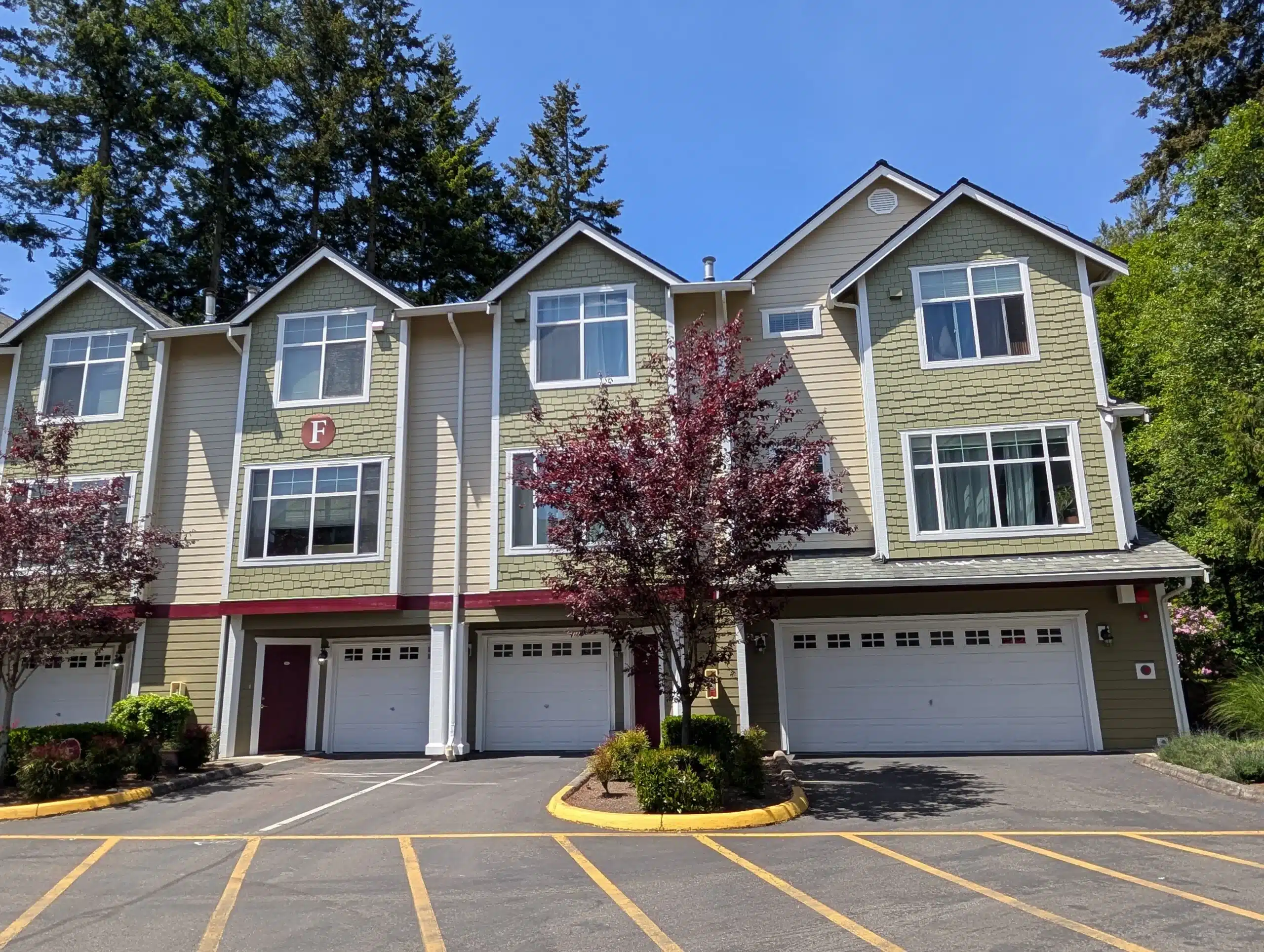 Exterior Commercial Painting and Siding Refresh Recently painted commercial townhouse building featuring updated green and beige siding, white trim, and clean exterior finishes.