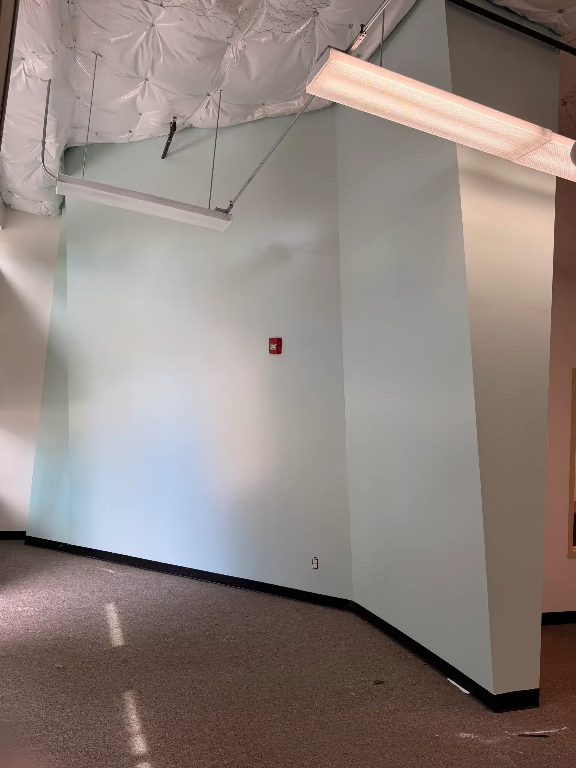 Commercial interior painting with light green accent walls Corner of a commercial office with freshly painted light green walls and exposed ceiling.