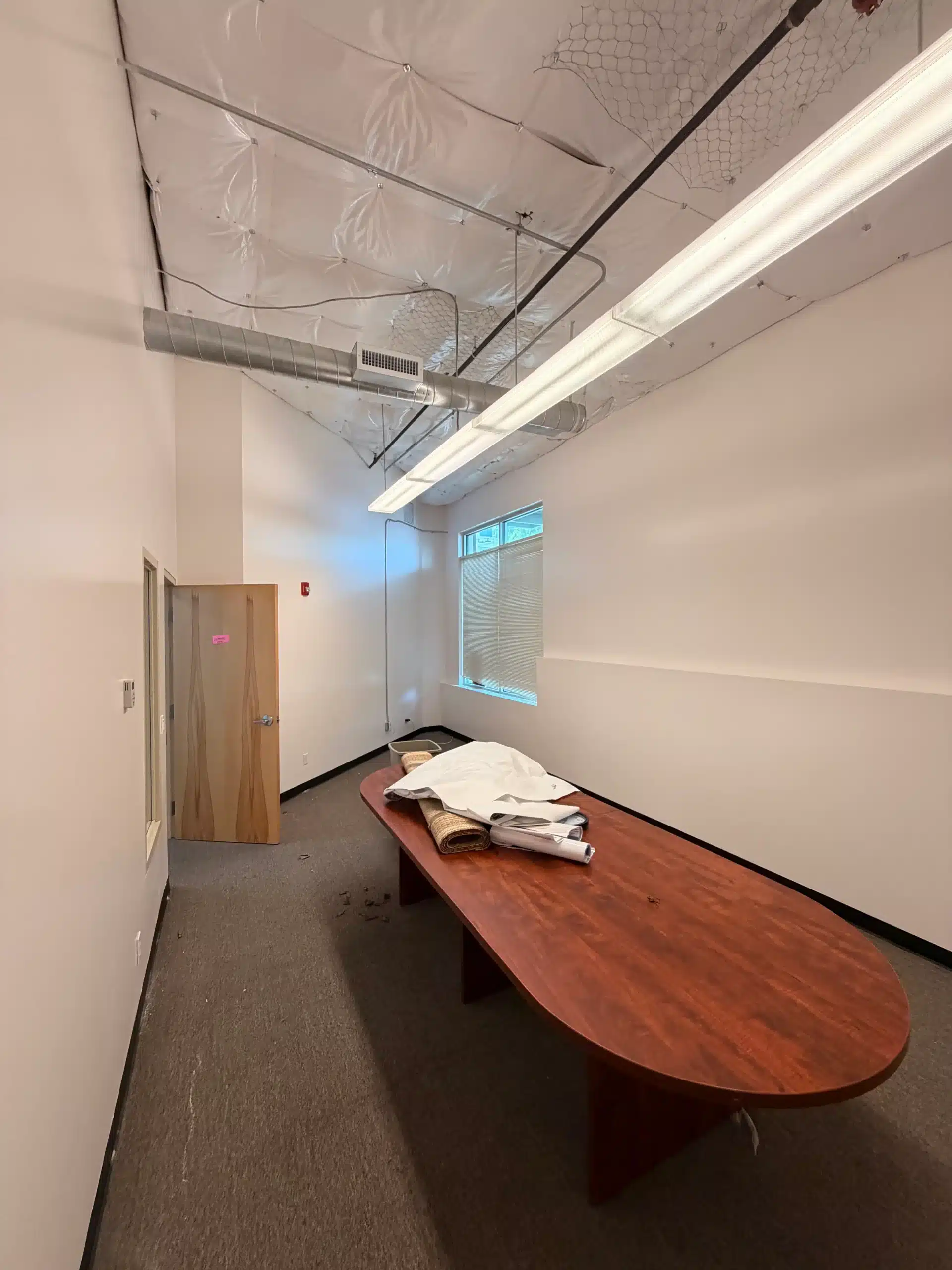 Professional Commercial Office Interior Painting An empty commercial office conference room with freshly painted white walls and a large wooden table.